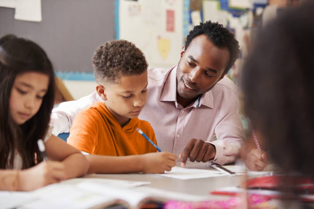 Male teacher working with elementary school boy