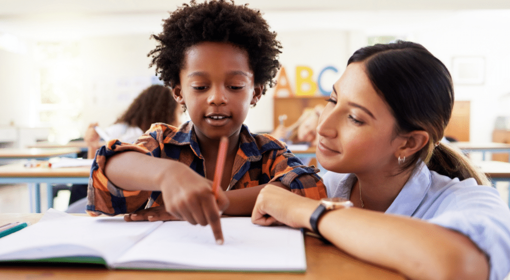 A teacher helping her pupil to read.