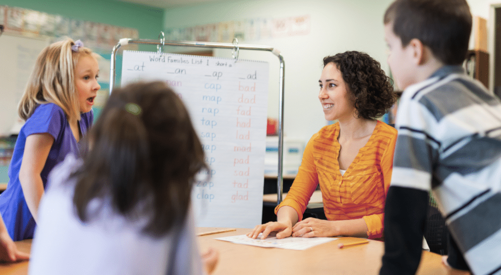 A teacher smiling with her students in a classroom.