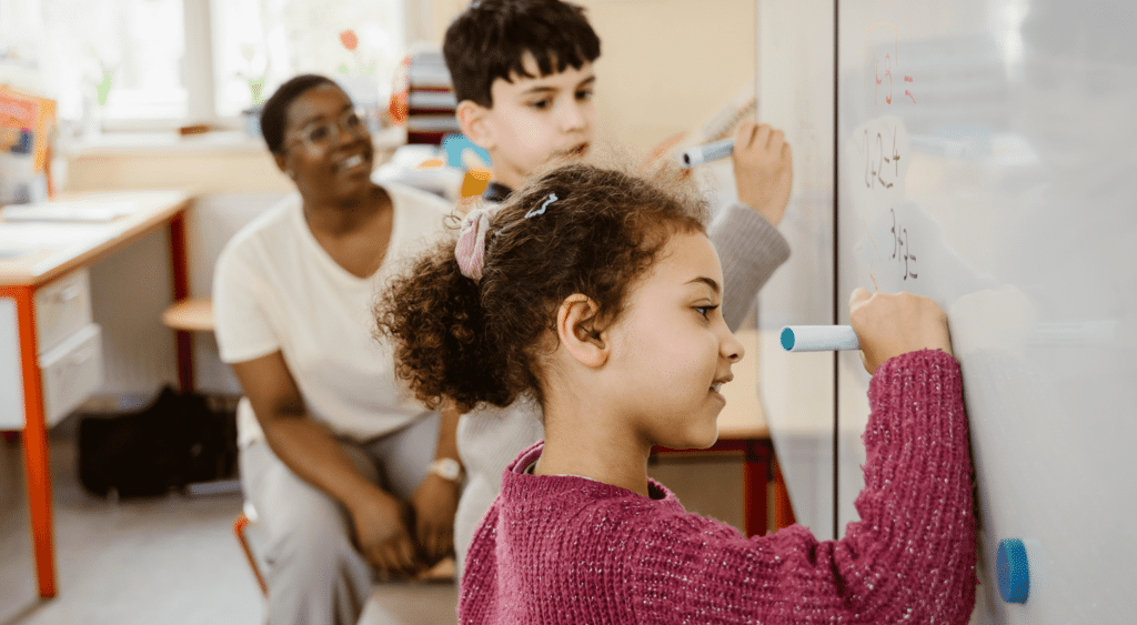 substitute teacher with two students at whiteboard