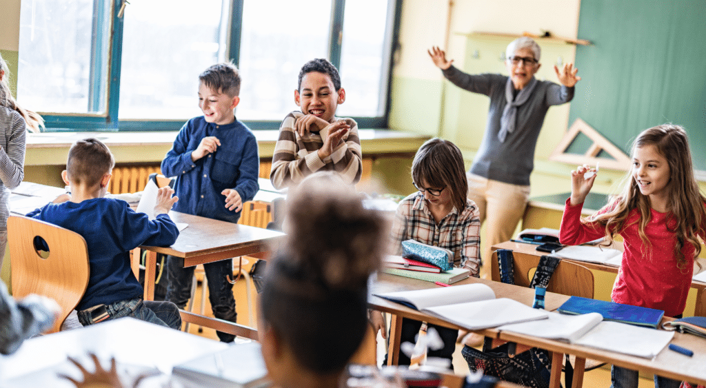 Elementary students playing in a classroom while substitute teacher attempts to get their attention