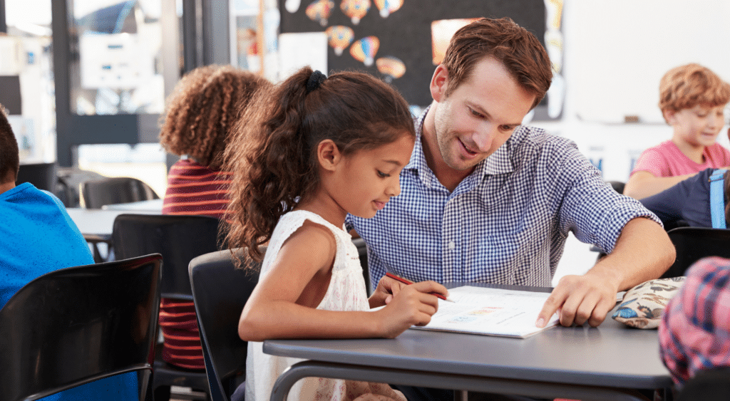 Teacher helps student with a test at their desk.