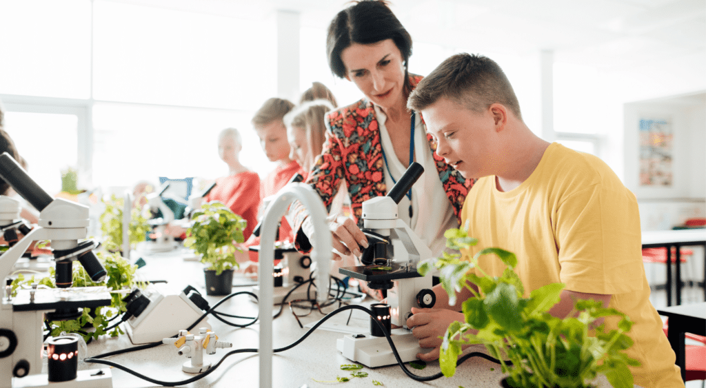 Teacher helps students use microscopes.