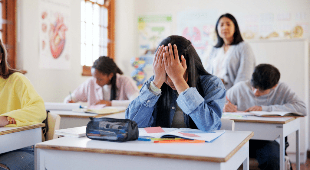 Student is sitting at their desk with their head in their hands.