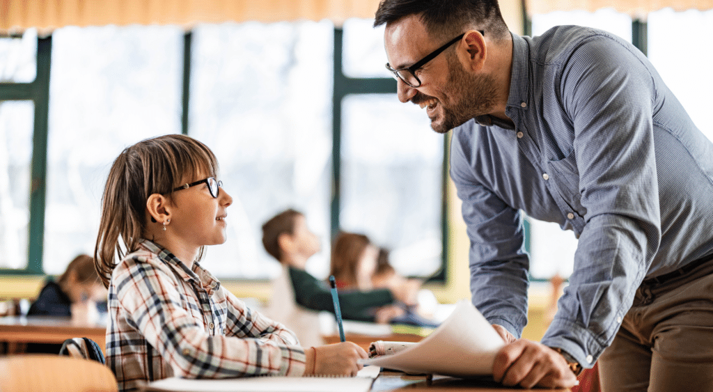 Teacher helping a student at their desk.